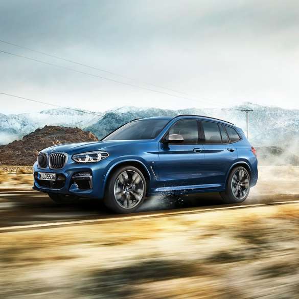 BMW X3 M40i, plano medio del rin y de la defensa frontal frente a una montaña BMW X3 M40i, plano medio del rin y de la defensa frontal frente a una montaña