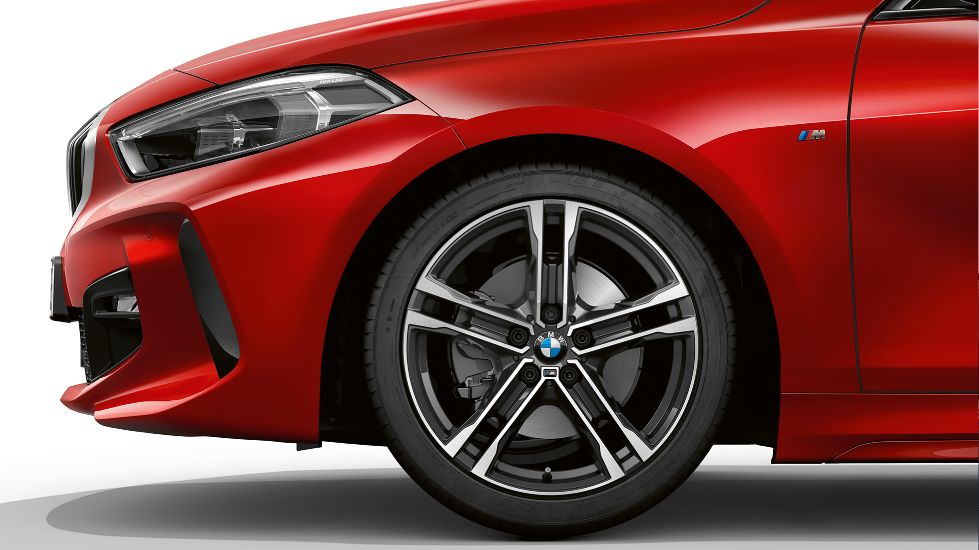 BMW Serie 1 Modelo M Sport, frontal de lado. BMW Serie 1 Modelo M Sport en Melbourne Red metálico, frontal desde el costado con llantas de aleación ligera M de 17 pulgadas Double-spoke estilo 550 M en Bicolor.