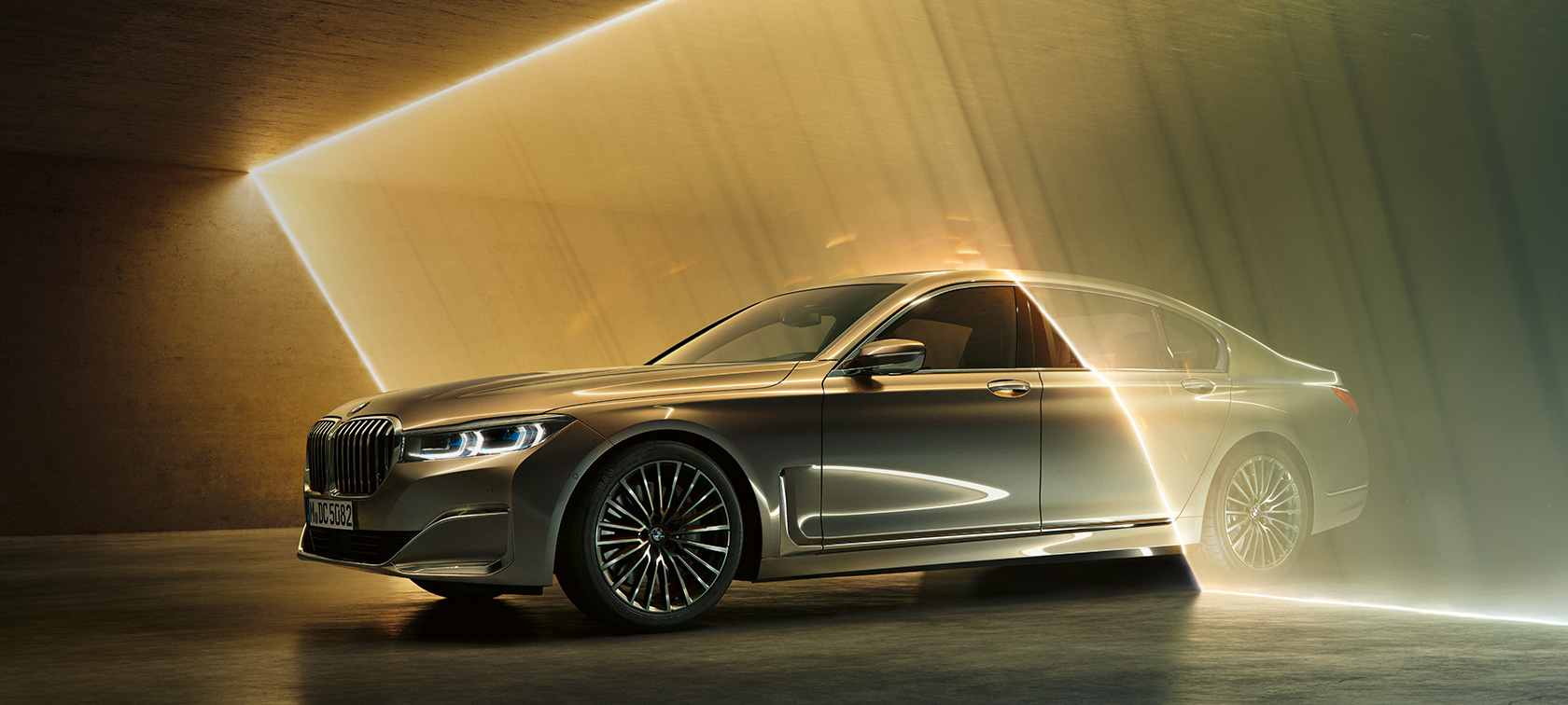 BMW Serie 7 Sedán vista frontal de tres cuartos BMW Serie 7 Sedán: BMW gris en vista frontal de tres cuartos rodeado por haces de luz