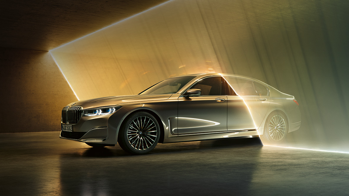 BMW Serie 7 Sedán en vista frontal de tres cuartos BMW Serie 7 Sedán: BMW gris en vista frontal de tres cuartos rodeado de haces de luz