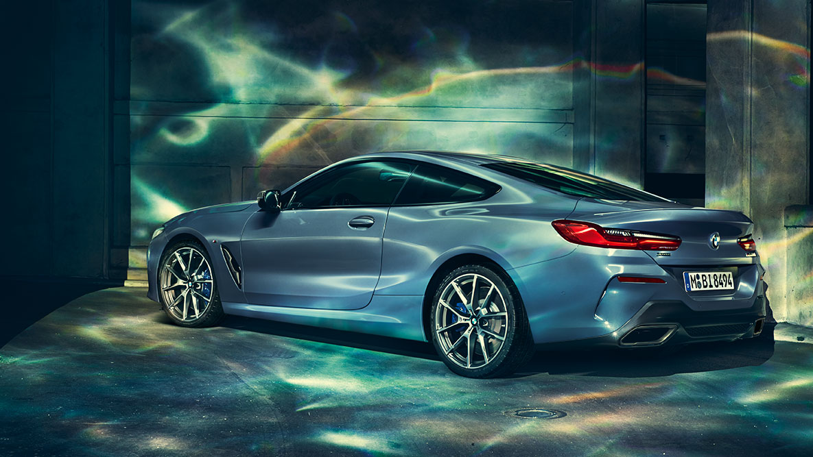 BMW Serie 8 Coupé, toma trasera de tres cuartos. Toma trasera de tres cuartos del BMW Serie 8 Coupé de noche frente a un escenario urbano.