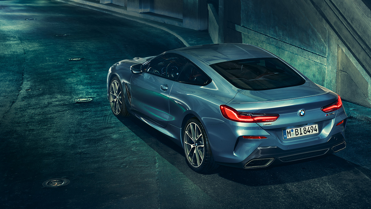 BMW Serie 8 Coupé, toma trasera de tres cuartos. Toma trasera de tres cuartos del BMW Serie 8 Coupé de noche frente a un escenario urbano.