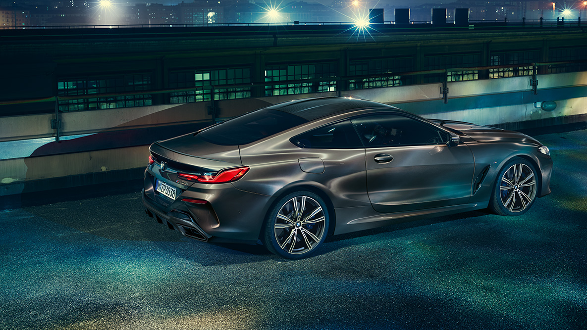 Toma fija del BMW Serie 8 Coupé. Toma fija del BMW Serie 8 Coupé con equipamiento BMW Individual desde un lado en un ambiente urbano nocturno.
