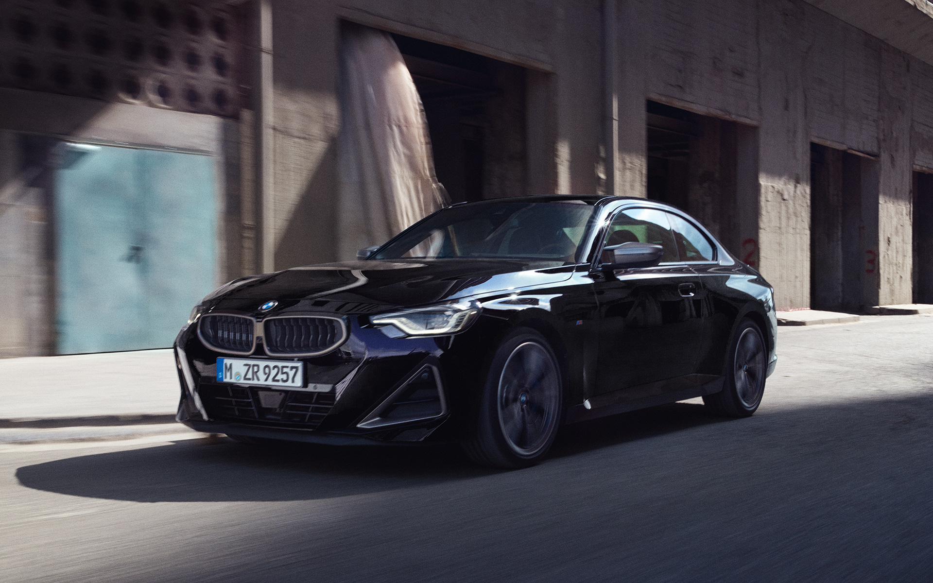 BMW M240i xDrive Coup&eacute; G42 2021 Black Sapphire metalizado Vista de tres cuartos del lateral, en marcha delante de un almac&eacute;n