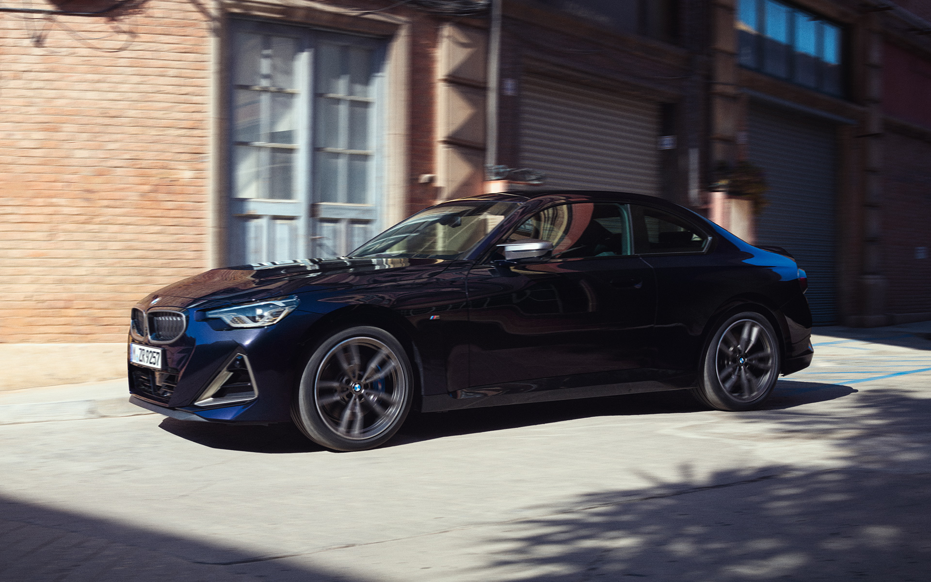 BMW M240i xDrive Coup&eacute; G42 2021 Black Sapphire metalizado Vista del lateral, parado delante de un almac&eacute;n