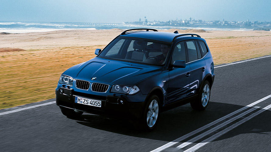 BMW X3 E83, primera generación, vista de tres cuartos del frontal, circulando por la calle Modelos BMW X BMW X3 E83, primera generación, vista de tres cuartos del frontal, circulando por la calle