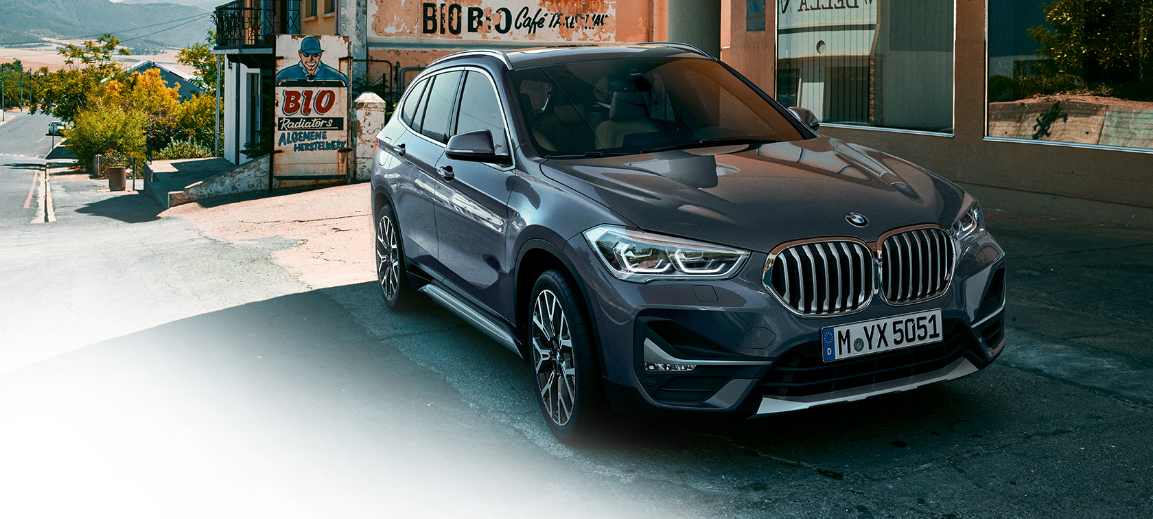 BMW X1, vista frontal tres cuartos. BMW X1, vista frontal tres cuartos frente a un escenario urbano.