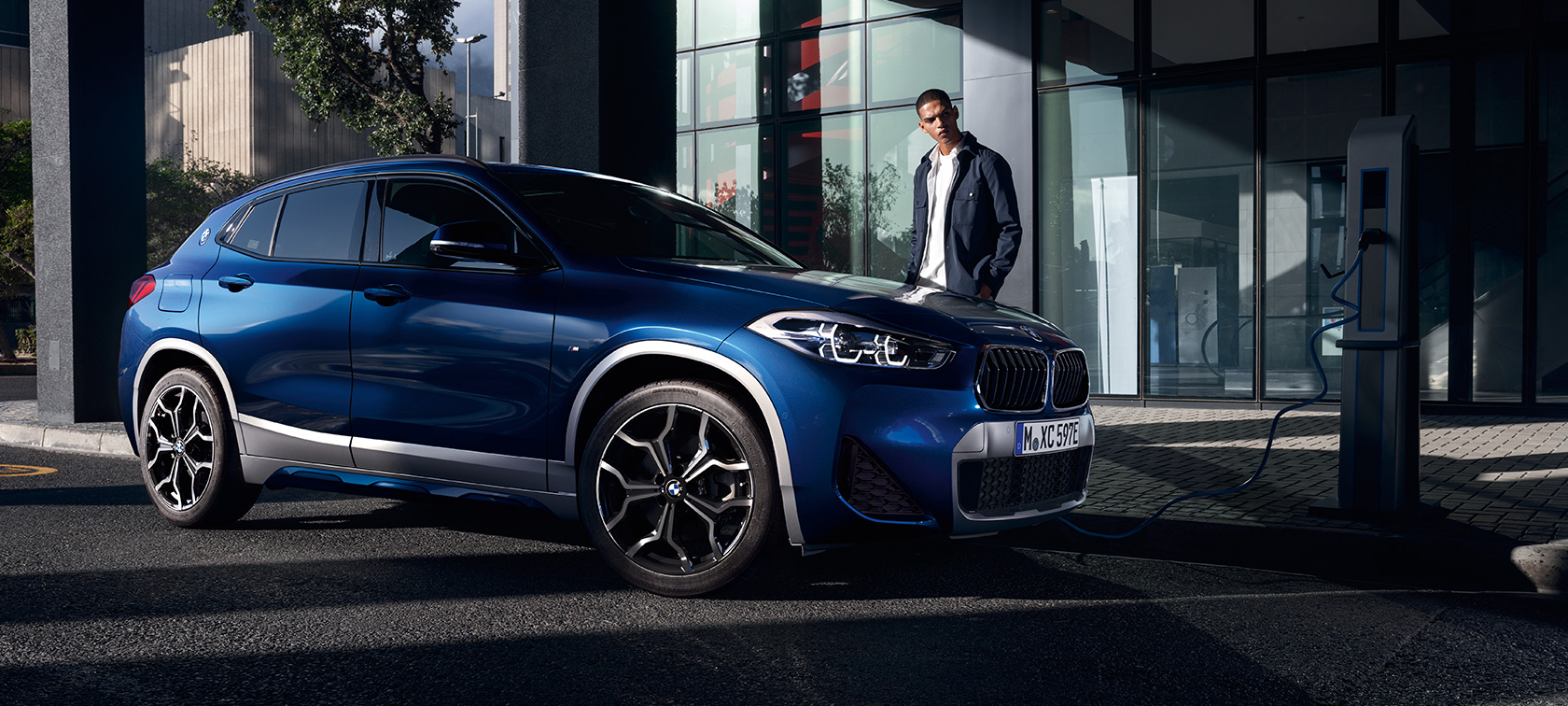 Híbrido enchufable BMW X2 xDrive25e F39, vista de tres cuartos del lateral, en punto de carga Híbrido enchufable BMW X2 xDrive25e F39, vista de tres cuartos del lateral, en punto de carga con modelo