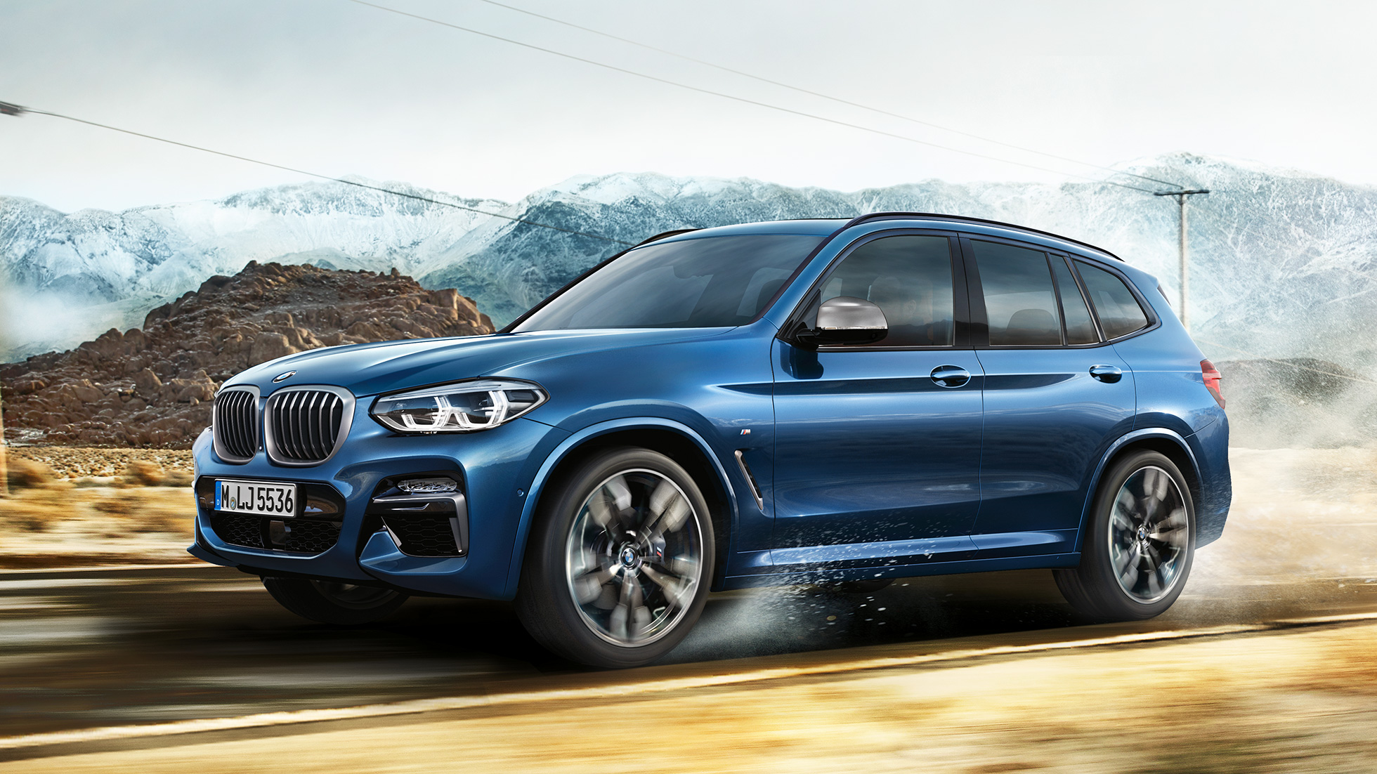 BMW X3 M40i, plano medio del rin y de la defensa frontal frente a una montaña BMW X3 M40i, plano medio del rin y de la defensa frontal frente a una montaña