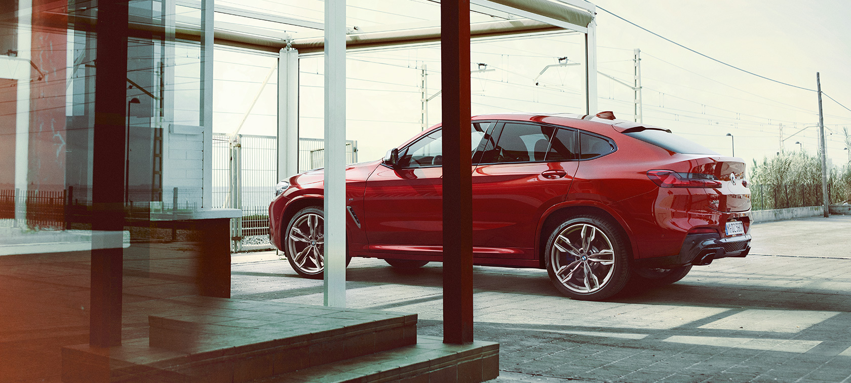 Vista lateral del BMW X4 Vista lateral del BMW X4 M40i 2018 Flamenco Red efecto brillante estacionándose