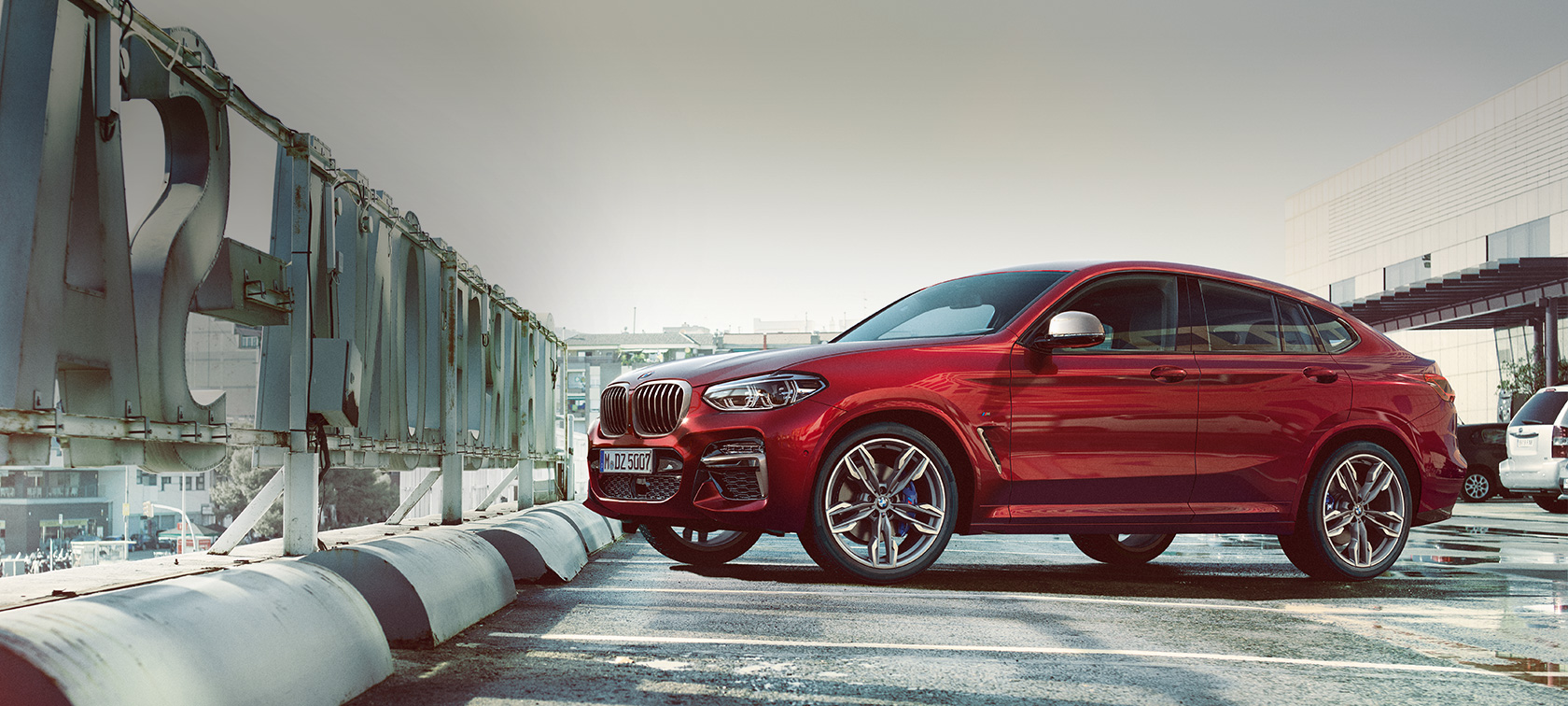 Vista lateral del BMW X4 estacionándose BMW X4 M40i 2018 Flamenco Red efecto brillante, vista lateral en estacionamiento
