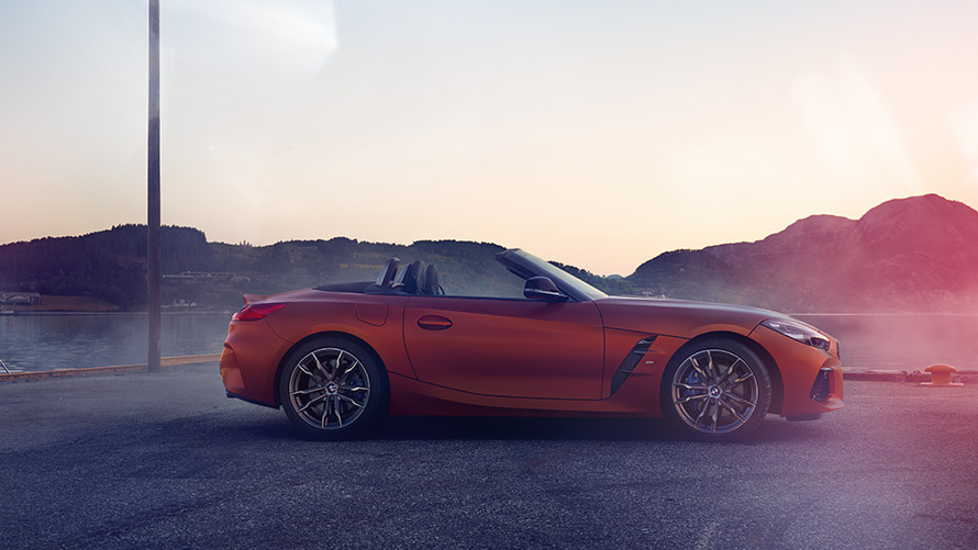 BMW Z4 naranja Primera Edición parado en curva BMW Z4 naranja Primera edición parado en curva frente a paisaje de montaña